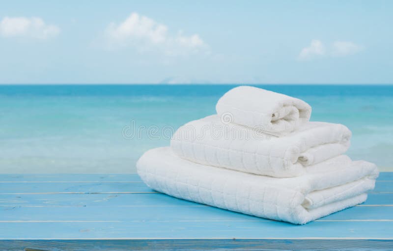 Vita strandhanddukar på trä över suddig blå havsbakgrund arkivfoto Vita strandhanddukar på trä över suddig blå havsbakgrund arkivfoto