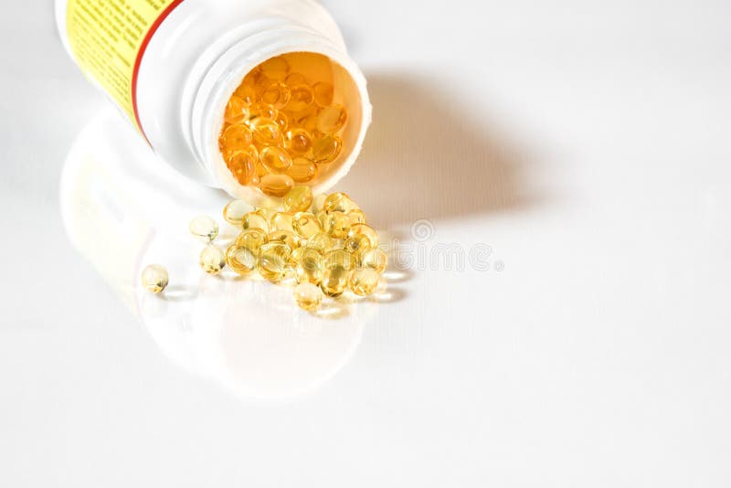 Vitamin D capsules spilled onto a white surface