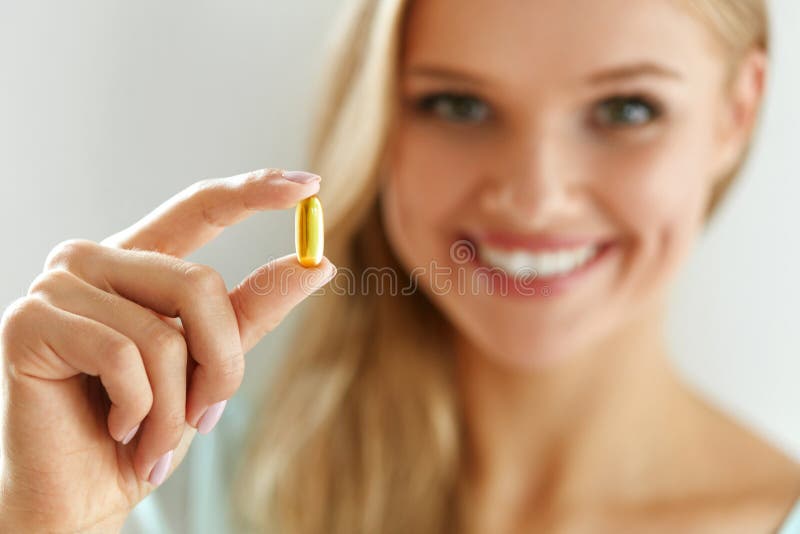 Vitamina y suplemento Mujer hermosa que sostiene la cápsula del aceite de pescado foto de archivo libre de regalías Vitamina y suplemento Mujer hermosa que sostiene la cápsula del aceite de pescado foto de archivo libre de regalías