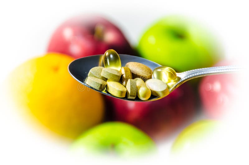 Assorted vitamins and nutritional supplements in serving spoon. on blur colorful fruits background. Assorted vitamins and nutritional supplements in serving spoon. on blur colorful fruits background