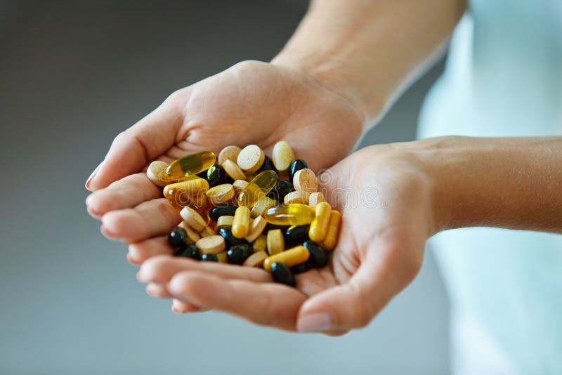 Vitaminas e suplementos A mulher entrega completamente de comprimidos da medicamentação fotografia de stock royalty free Vitaminas e suplementos A mulher entrega completamente de comprimidos da medicamentação fotografia de stock royalty free