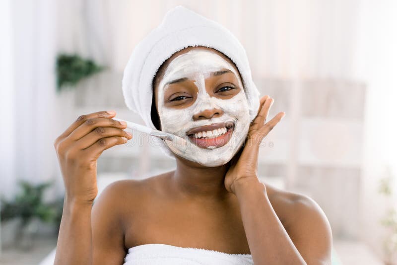 Vitamin facial mask. African smiling woman with a face in a mask in spa. Vitamin facial mask. African smiling woman with a face in a mask in spa.