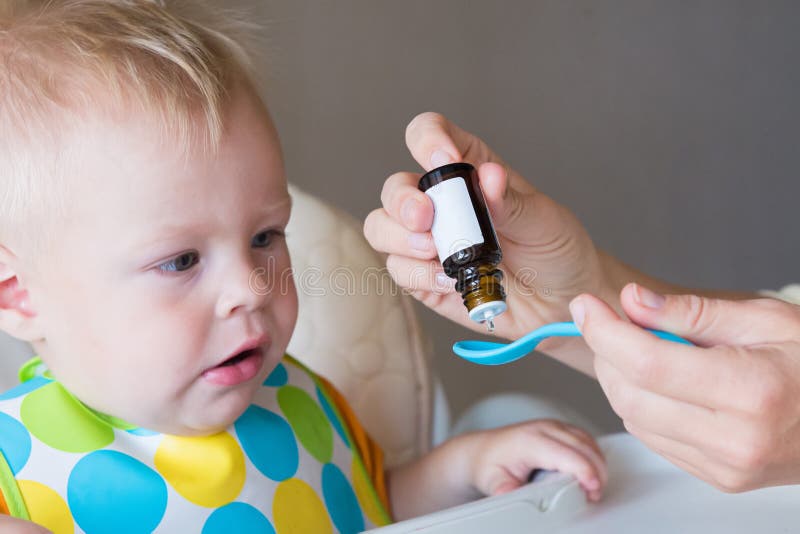 Vitamins for young children. mom drips vitamins into a spoon while feeding her little son. healthy childhood royalty free stock image Vitamins for young children. mom drips vitamins into a spoon while feeding her little son. healthy childhood royalty free stock image