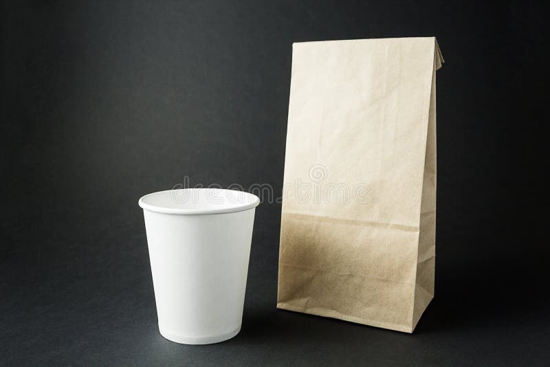 Vitbokkoppar och en packande påse från återanvänd pappers- orientering på en svart bakgrund, utrymme för text eller etikett royaltyfri fotografi Vitbokkoppar och en packande påse från återanvänd pappers- orientering på en svart bakgrund, utrymme för text eller etikett royaltyfri fotografi