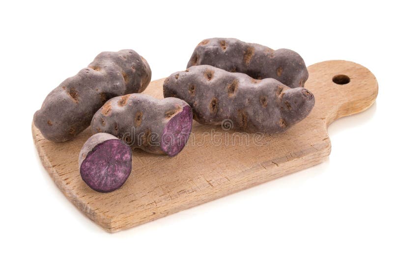 Vitelotte, purpere aardappel in stapels op een houten scherpe raad stock fotografie Vitelotte, purpere aardappel in stapels op een houten scherpe raad stock fotografie