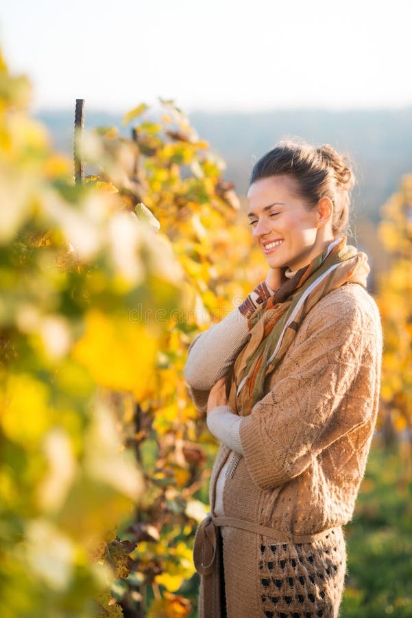 Viticoltore rilassato della donna che sta nella vigna all'aperto in autunno fotografia stock Viticoltore rilassato della donna che sta nella vigna all'aperto in autunno fotografia stock