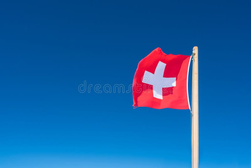 Vlag van Zwitserland tegen de achtergrond van de blauwe hemel Bovenkant van Jungfrau stock afbeelding Vlag van Zwitserland tegen de achtergrond van de blauwe hemel Bovenkant van Jungfrau stock afbeelding