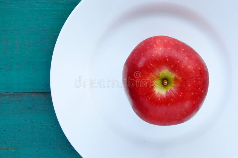 Vlak leg mening van een verse rode appel die op een witte plaat wordt gediend stock fotografie Vlak leg mening van een verse rode appel die op een witte plaat wordt gediend stock fotografie