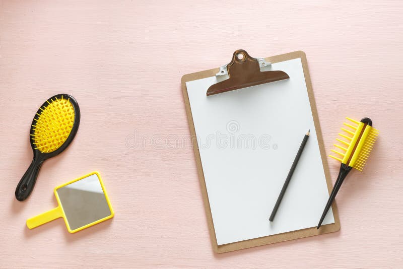 Flat lay of hair comb crest brushes with handle for all types, pocket mirror and folder tablet with pencil, on pink copy space background. Minimalistic feminine flat lay for bloggers, designers, sites. Flat lay of hair comb crest brushes with handle for all types, pocket mirror and folder tablet with pencil, on pink copy space background. Minimalistic feminine flat lay for bloggers, designers, sites.