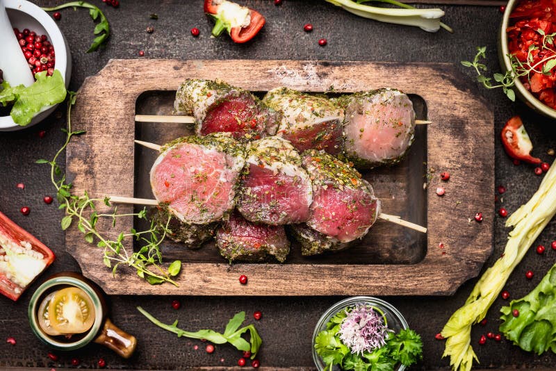 Vleesvleespennen met groene kruidenkorst voor grill of het koken, voorbereiding op donkere rustieke houten achtergrond stock afbeelding Vleesvleespennen met groene kruidenkorst voor grill of het koken, voorbereiding op donkere rustieke houten achtergrond stock afbeelding