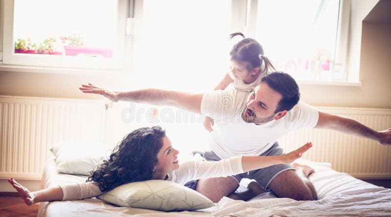 Vlieg in bed De jonge ouders hebben spel met meisje stock afbeeldingen Vlieg in bed De jonge ouders hebben spel met meisje stock afbeeldingen