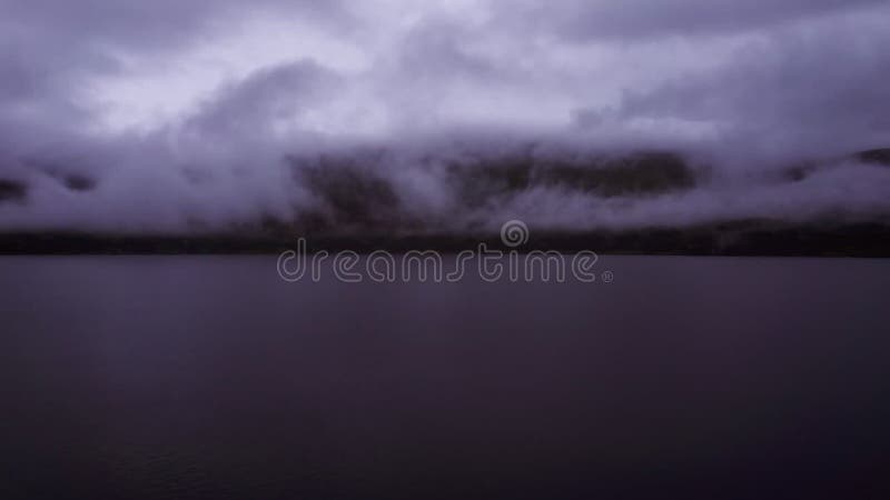 Vliegen over de treetops en het bergmeer bij nacht met een lage wolk boven het wateroppervlak in scandinavië