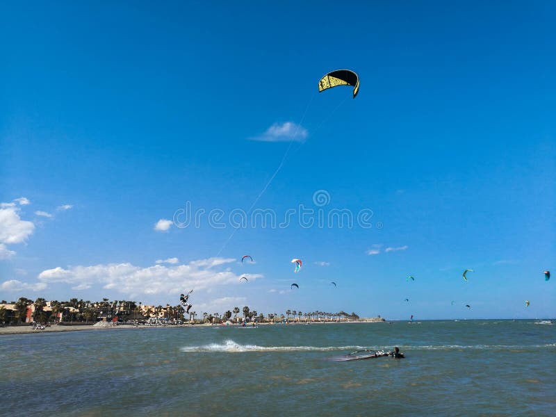 Vlieger inschepende sportman hoog met vlieger en kiteboard in laarzen in de blauwe hemel vliegen, actieve sporten en levensstijl royalty-vrije stock afbeelding Vlieger inschepende sportman hoog met vlieger en kiteboard in laarzen in de blauwe hemel vliegen, actieve sporten en levensstijl royalty-vrije stock afbeelding