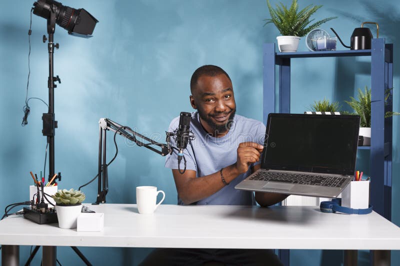 Vlogger presenting and testing laptop. Vlogger presenting laptop and testing features while creating web content for internet channel. Smiling blogger showing portable computer giveaway gift while recording video