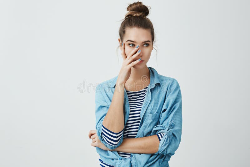 Você embaraçado mim na frente dos amigos Retrato da mulher europeia nova irritada no penteado do bolo e na camisa da sarja de Nim imagens de stock Você embaraçado mim na frente dos amigos Retrato da mulher europeia nova irritada no penteado do bolo e na camisa da sarja de Nim imagens de stock