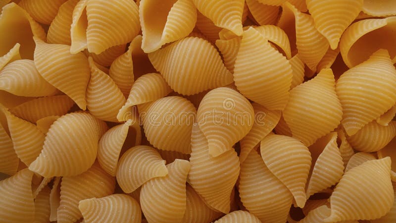 Voedselachtergrond met droge conchiglie rigate deegwaren, een populaire Italiaanse zeeschelp of shell deegwaren stock foto Voedselachtergrond met droge conchiglie rigate deegwaren, een populaire Italiaanse zeeschelp of shell deegwaren stock foto