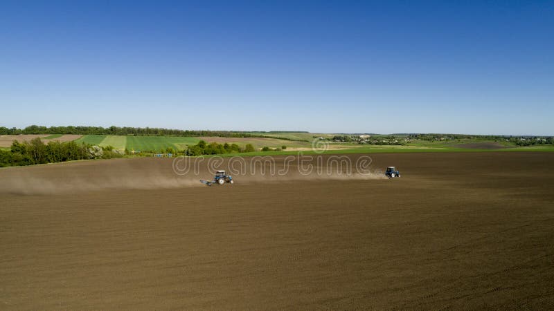 Tractors plows a field in the spring accompanied by plow. Tractors plowing a field and makes a lot of dust. Tractors plows a field in the spring accompanied by plow. Tractors plowing a field and makes a lot of dust.