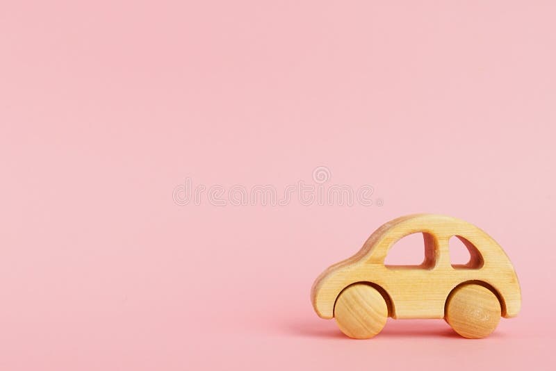 Voiture de bébé en bois sur un fond en pastel rose avec le copyspace photographie stock libre de droits Voiture de bébé en bois sur un fond en pastel rose avec le copyspace photographie stock libre de droits