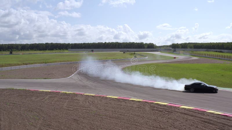 Voiture de vue aérienne dérivant avec de la fumée provenant de pneus brûlés sur la piste de vitesse banque de vidéos