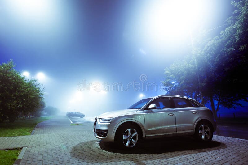 Voiture garée sur une rue de ville de nuit couverte de brouillard, ville brouillée images stock Voiture garée sur une rue de ville de nuit couverte de brouillard, ville brouillée images stock