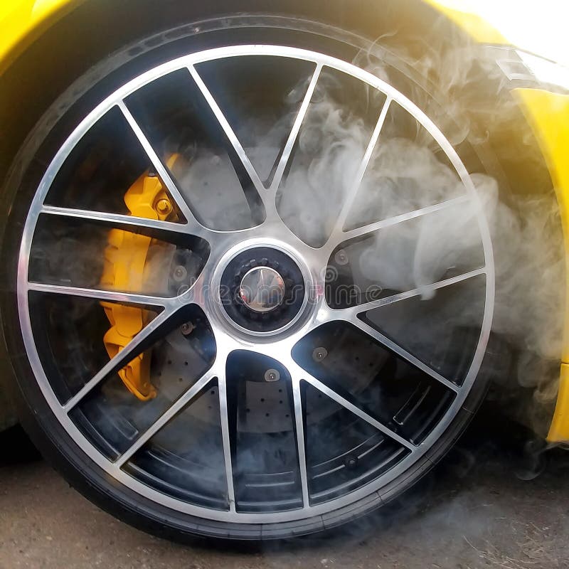 Voiture jaune avec des roues d'alliage léger avec les freins en céramique de carbone et fumée de elle Étroitement, image carrée