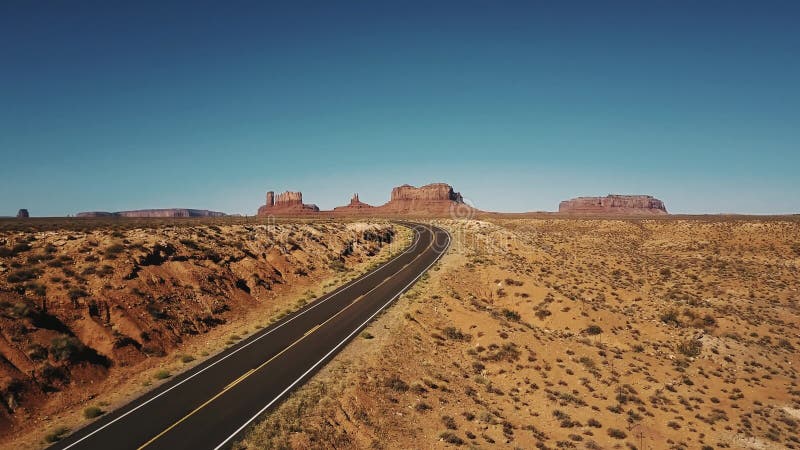 Vol de bourdon laissé au-dessus du tour vide de route de route de désert de grès en vallée de monuments, Arizona avec les montagn