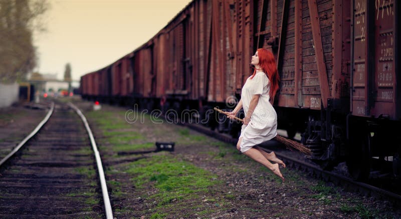 Redhead witch flying on the broom on train station. Redhead witch flying on the broom on train station