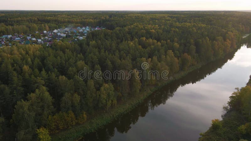 Vol sur un quadricoptère au-dessus d'une rivière calme au coucher du soleil et en forêt.