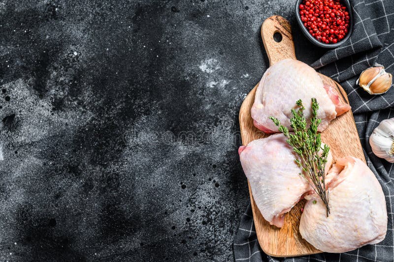 Raw chicken thigh, organic poultry meat. Black background. Top view. Copy space. Raw chicken thigh, organic poultry meat. Black background. Top view. Copy space.