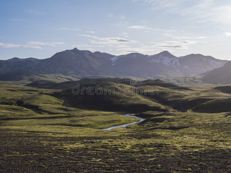 Volcanic landscape with blue river, snow covered mountains, green hills and lava gravel ground covered by lush moss royalty free stock photos Volcanic landscape with blue river, snow covered mountains, green hills and lava gravel ground covered by lush moss royalty free stock photos