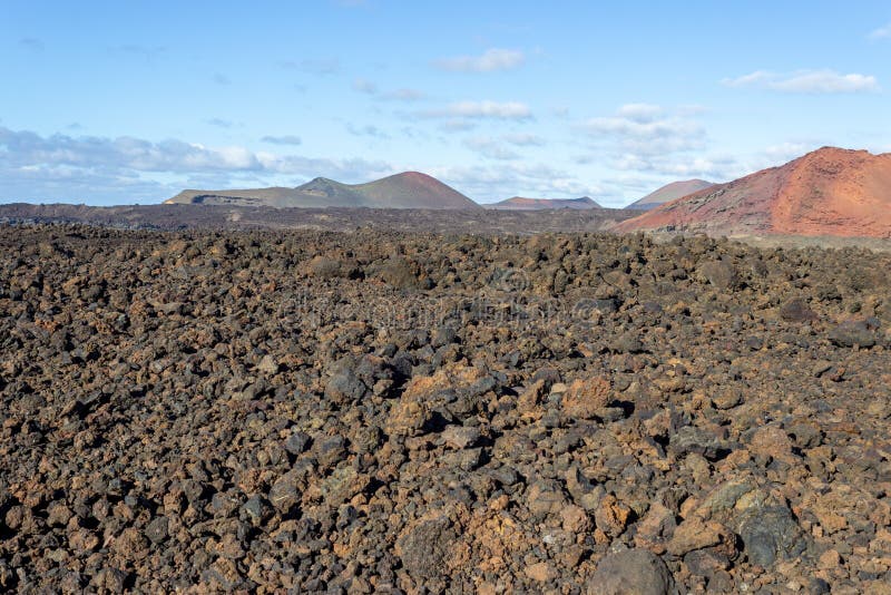 Volcanic landscape with lava field in the foreground and mountain range with different red and brown colours in the background on royalty free stock photography Volcanic landscape with lava field in the foreground and mountain range with different red and brown colours in the background on royalty free stock photography