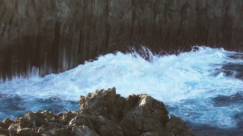 Volcanic vertical cliff and waves breaking