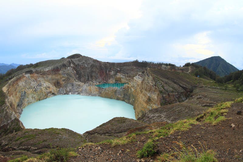 White acid-saline lake Tap - Tiwu Ata Polo - and green cool acid-brine lake Tin - Tiwu Nua Moori Koohi Fah - colored by volcanic gases in volcanoes of mountain Kelimutu during sunrise on Flores, Nusa Tengara Timur - NTT, Indonesia. White acid-saline lake Tap - Tiwu Ata Polo - and green cool acid-brine lake Tin - Tiwu Nua Moori Koohi Fah - colored by volcanic gases in volcanoes of mountain Kelimutu during sunrise on Flores, Nusa Tengara Timur - NTT, Indonesia