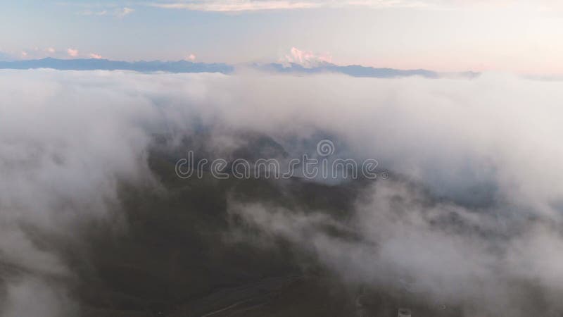 Voler au-dessus des nuages au crépuscule ou à l'aube Voler au-dessus des nuages en direction d'une haute montagne neigeuse aérien clips vidéos