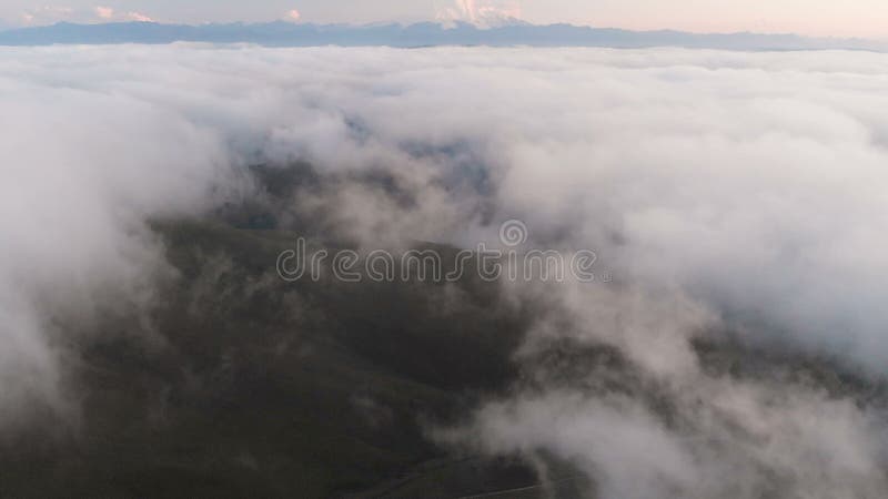 Voler au-dessus des nuages au crépuscule ou à l'aube Voler au-dessus des nuages en direction d'une haute montagne neigeuse aérien banque de vidéos