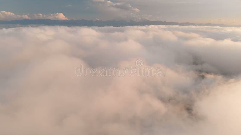 Voler au-dessus des nuages au crépuscule ou à l'aube Voler au-dessus des nuages en direction d'une haute montagne neigeuse aérien clips vidéos