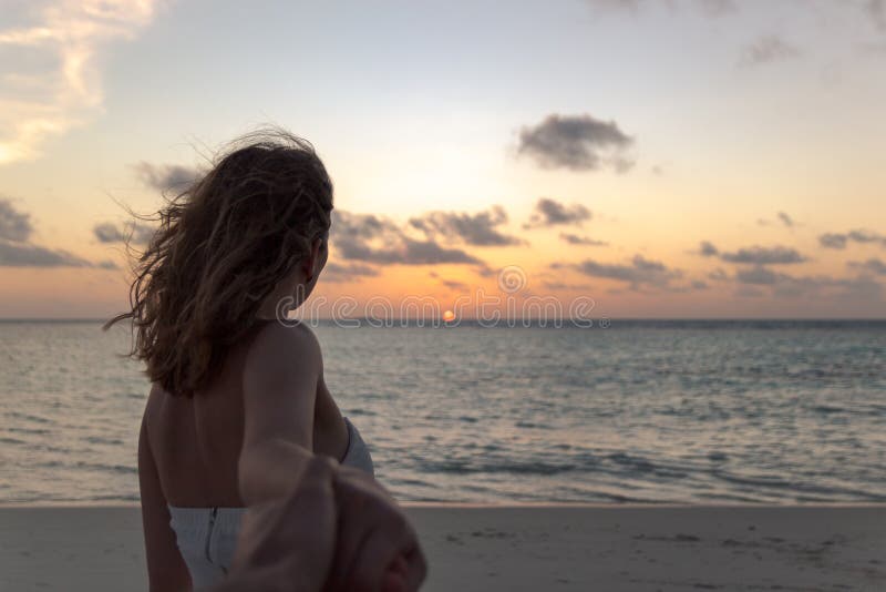 Volg me concept jonge vrouw die op een strand zonsondergang bekijken stock afbeelding Volg me concept jonge vrouw die op een strand zonsondergang bekijken stock afbeelding