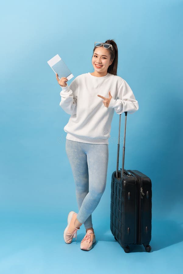 Volledig lengtebeeld van het Vrolijke vrouw dragen in toevallige kleding die met bagage en kaartjes over blauwe achtergrond voorb royalty-vrije stock fotografie Volledig lengtebeeld van het Vrolijke vrouw dragen in toevallige kleding die met bagage en kaartjes over blauwe achtergrond voorb royalty-vrije stock fotografie