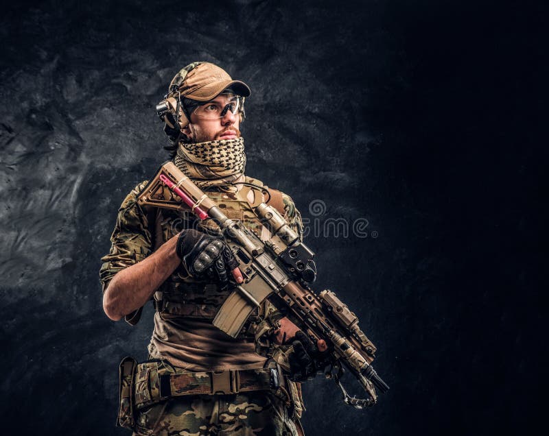 Volledig uitgeruste militair in camouflage eenvormige holding een aanvalsgeweer Studiofoto tegen een donkere muur stock fotografie Volledig uitgeruste militair in camouflage eenvormige holding een aanvalsgeweer Studiofoto tegen een donkere muur stock fotografie