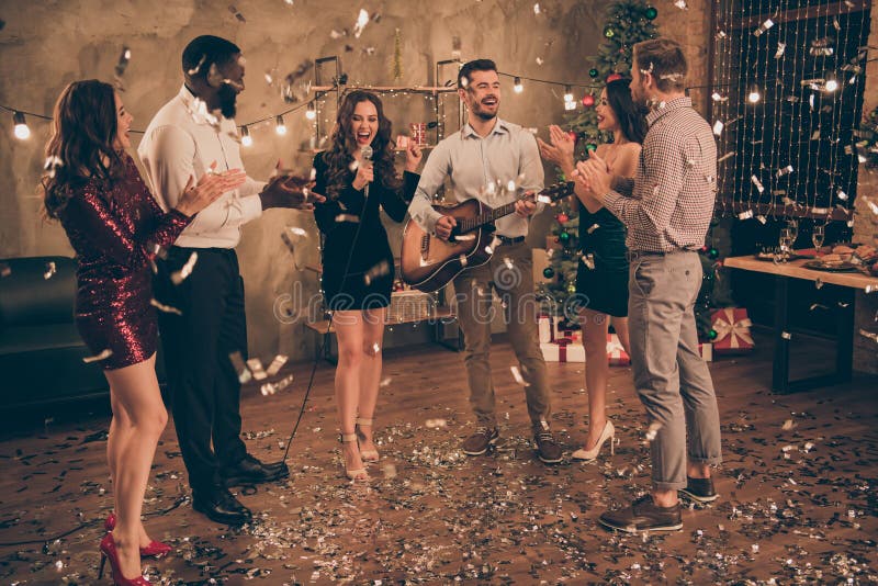 Full length photo of group of students hear pop starts play guitar enjoy, christmas party x-mas night in house with confetti falling indoors. Full length photo of group of students hear pop starts play guitar enjoy, christmas party x-mas night in house with confetti falling indoors