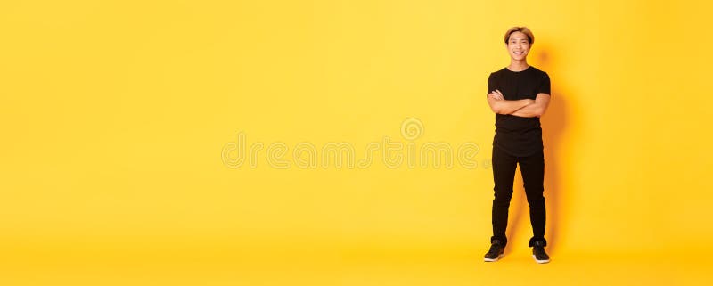 Voller Länge lächelnder, selbstbewusster asiatischer Blong-Mann Armstreifen über gelbem Hintergrund stockfoto