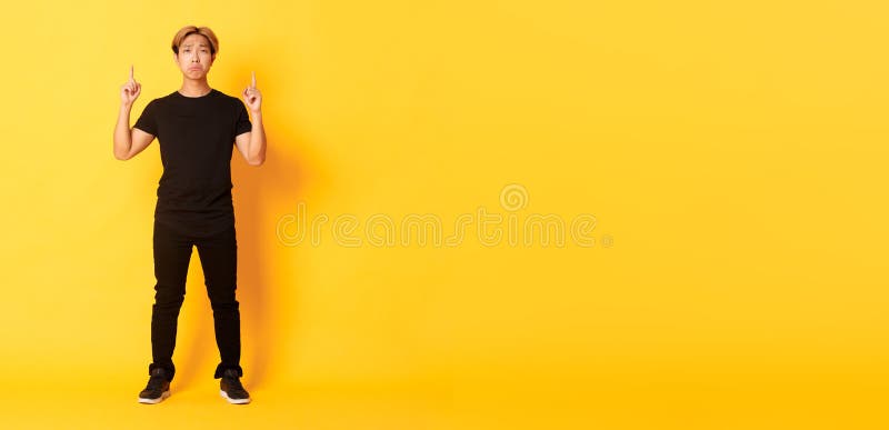 Voller trauriger, gut aussehender koreanischer Kerl mit blonden Haaren, der verärgerte Grimassen mit den aufgesetzten Fingern zeig stockbild