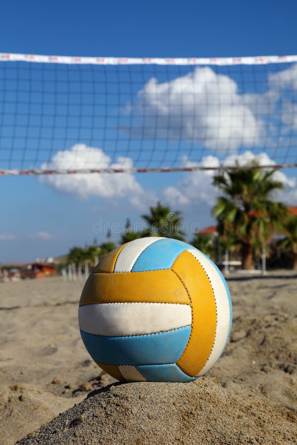 Volleyball net, volleyball on beach and palm trees. focus on ball