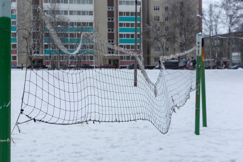 Volleyballnetz im Winter Schneetag, vor einem verwischten Hintergrund von Häusern und Wäldern auf dem Land lizenzfreies stockbild Volleyballnetz im Winter Schneetag, vor einem verwischten Hintergrund von Häusern und Wäldern auf dem Land lizenzfreies stockbild