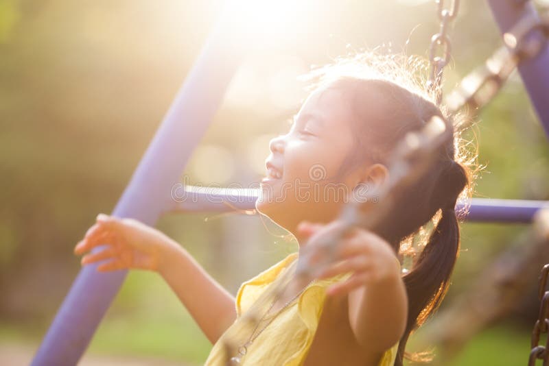 Volo asiatico felice della ragazza del piccolo bambino sull'oscillazione in campo da giuoco immagine stock Volo asiatico felice della ragazza del piccolo bambino sull'oscillazione in campo da giuoco immagine stock