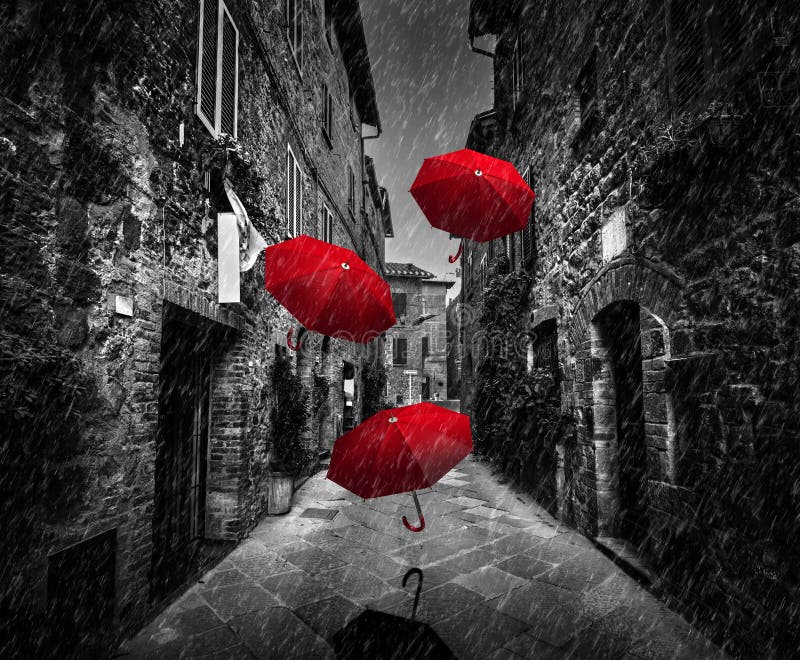 Volo di Umrbellas con il vento e la pioggia sulla via scura in una vecchia città italiana in Toscana, Italia immagini stock Volo di Umrbellas con il vento e la pioggia sulla via scura in una vecchia città italiana in Toscana, Italia immagini stock