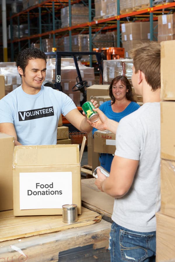 Voluntarios que recogen donaciones de la comida en Warehouse fotos de archivo Voluntarios que recogen donaciones de la comida en Warehouse fotos de archivo