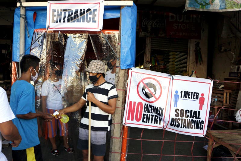 A volunteer at the entrance of a public market spray alcohol during the Covid 19 virus outbreak