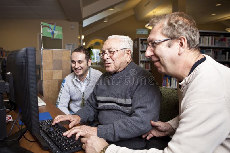 Volunteers teaching a senior how to use a computer