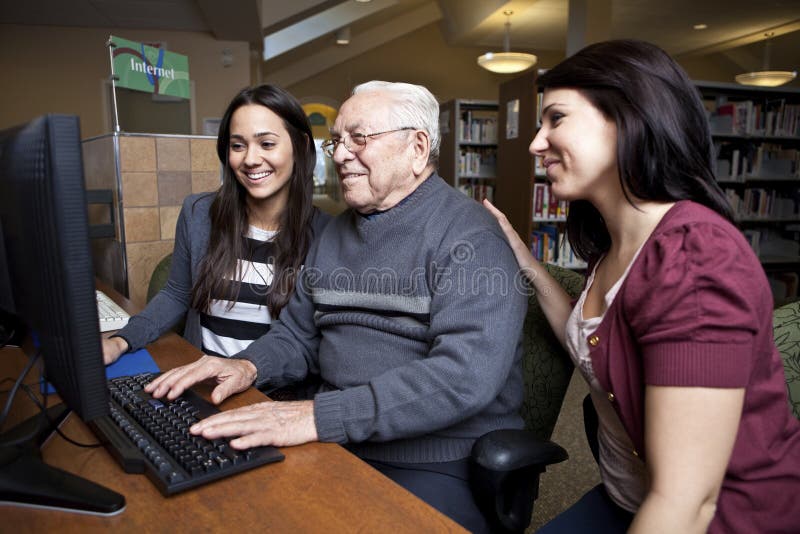 Volunteers teaching a senior how to use a computer